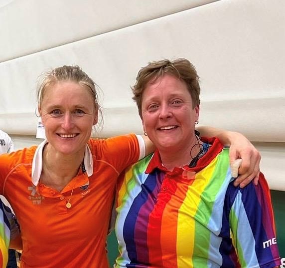 Case Manager, Laura in a rainbow striped shirt, with hockey legend, Marieke Dijkstra, ready to umpire at the hockey world cup.